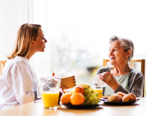 nurse serving meal to elderly woman